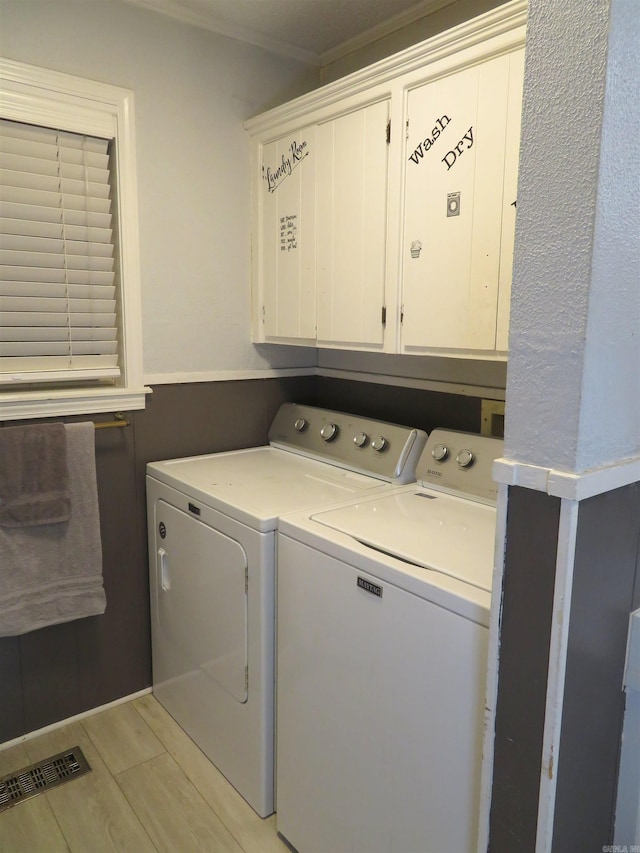 laundry room featuring cabinets, light hardwood / wood-style flooring, ornamental molding, and washer and clothes dryer