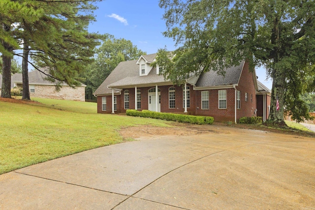 cape cod home featuring brick siding and a front yard