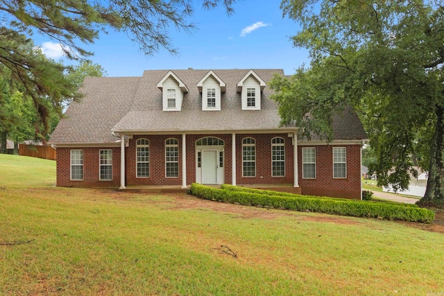 cape cod home with brick siding, a shingled roof, a porch, and a front yard