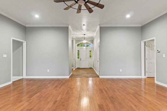 foyer entrance with ornamental molding, light wood finished floors, ceiling fan with notable chandelier, and baseboards