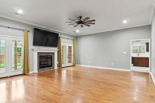 unfurnished living room featuring ornamental molding, light wood-style flooring, and a ceiling fan