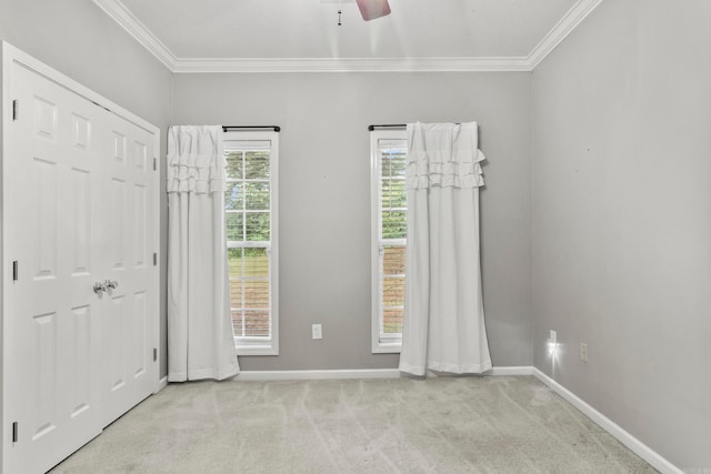 carpeted empty room with ornamental molding, a ceiling fan, and baseboards