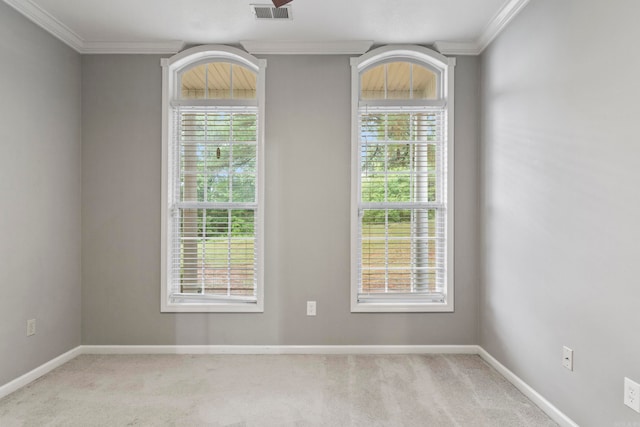 carpeted empty room with baseboards, visible vents, and crown molding