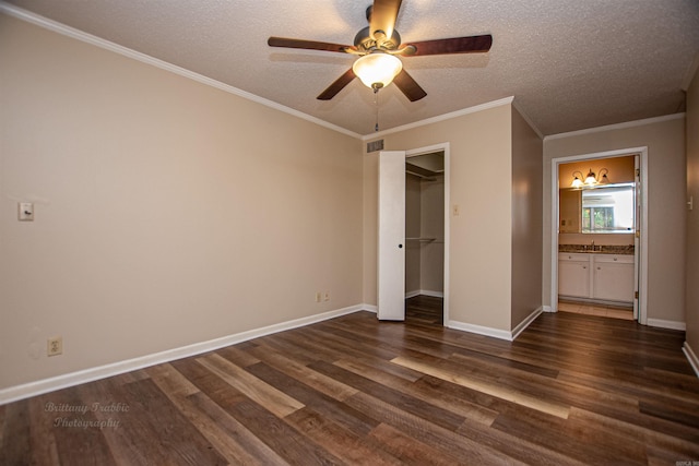 unfurnished bedroom featuring a textured ceiling, a walk in closet, dark hardwood / wood-style flooring, ensuite bathroom, and ceiling fan