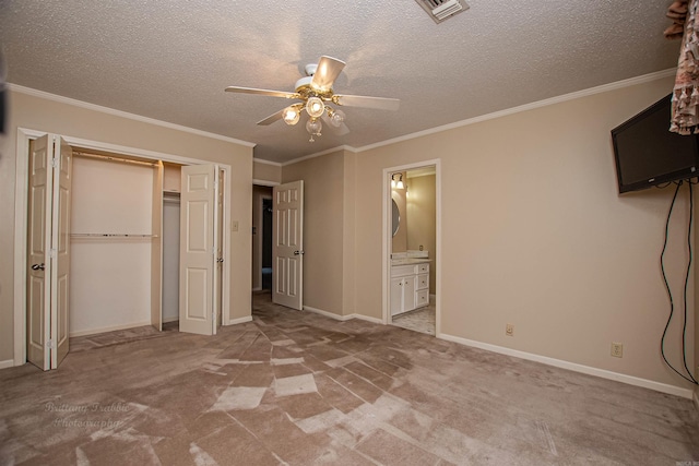 unfurnished bedroom with crown molding, a textured ceiling, ceiling fan, a closet, and light colored carpet