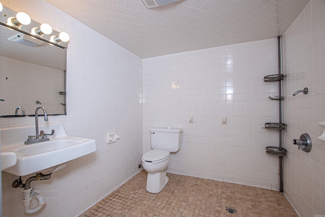 bathroom featuring tile walls, toilet, sink, and tile patterned flooring