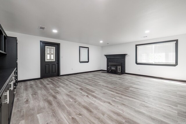 unfurnished living room featuring light hardwood / wood-style flooring and a wood stove