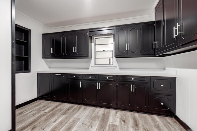 clothes washing area featuring light wood-type flooring and crown molding