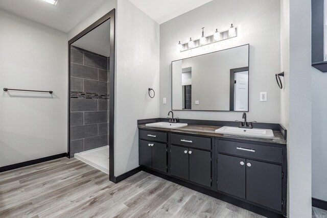 bathroom with hardwood / wood-style flooring, a tile shower, and vanity