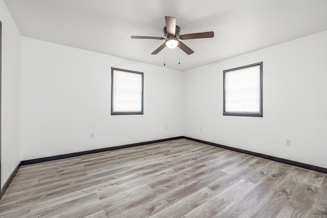 empty room with a wealth of natural light, ceiling fan, and light hardwood / wood-style floors