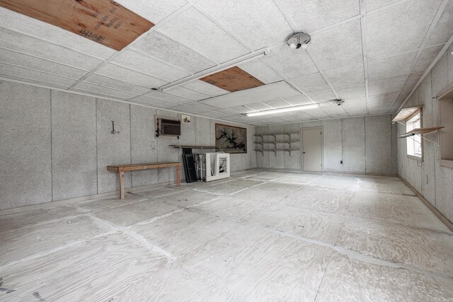 basement featuring a paneled ceiling and a wall mounted AC