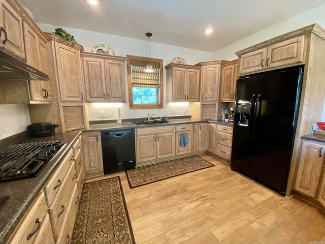 kitchen featuring light wood-type flooring, pendant lighting, backsplash, black appliances, and sink