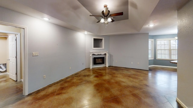 unfurnished living room featuring a raised ceiling and ceiling fan