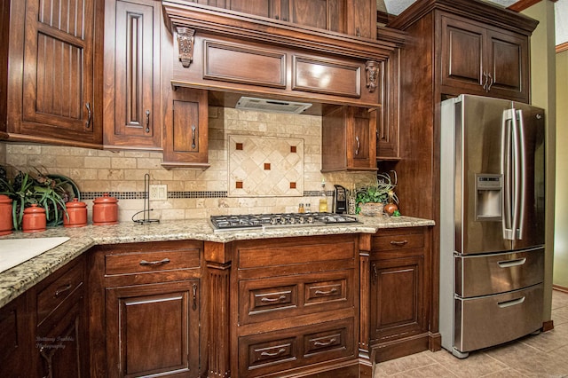 kitchen featuring appliances with stainless steel finishes, custom exhaust hood, backsplash, and light stone countertops