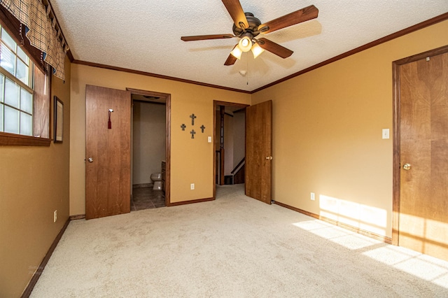 unfurnished bedroom with a textured ceiling, carpet floors, ornamental molding, and baseboards