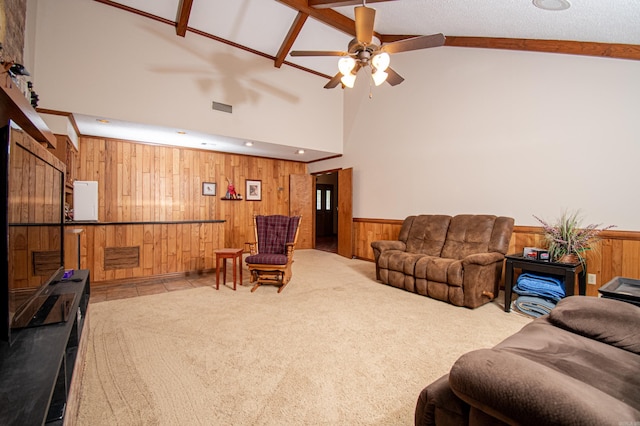 living room with light colored carpet, ceiling fan, wood walls, and high vaulted ceiling