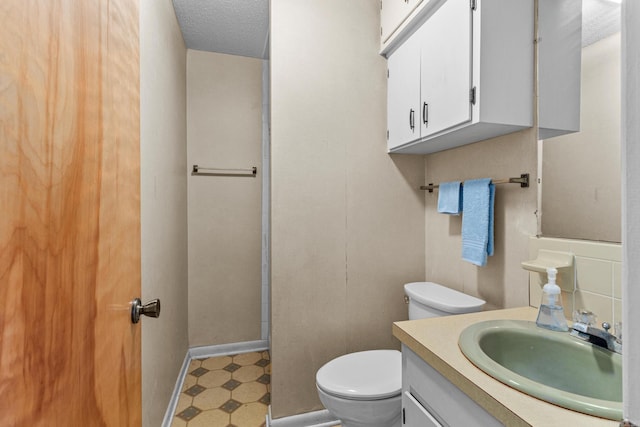 bathroom featuring vanity, toilet, and a textured ceiling