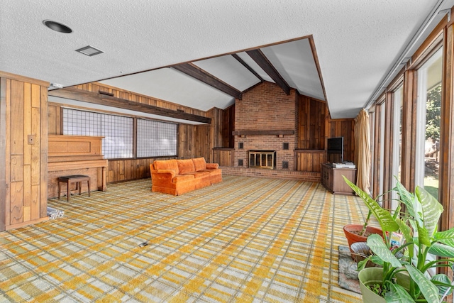 unfurnished living room featuring lofted ceiling with beams, wooden walls, a fireplace, and a textured ceiling