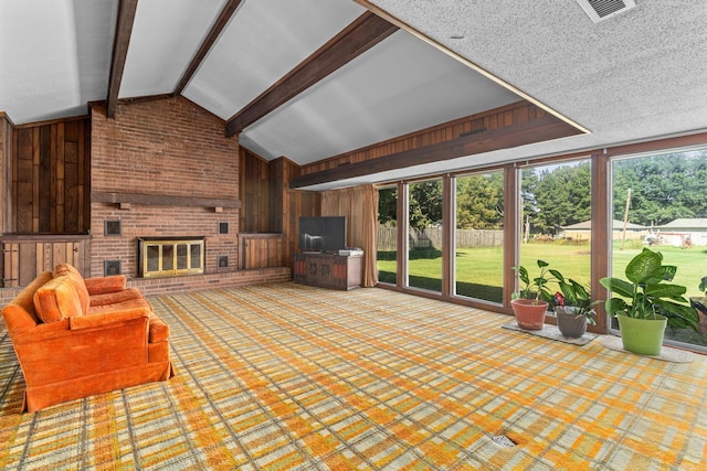 interior space with a brick fireplace, lofted ceiling with beams, and a wealth of natural light