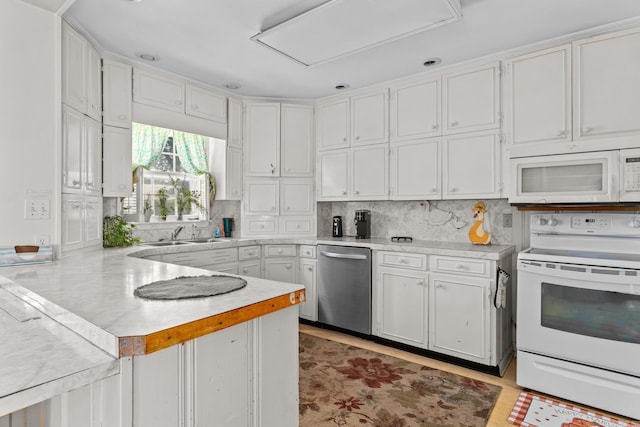 kitchen with tasteful backsplash, white appliances, sink, kitchen peninsula, and white cabinets