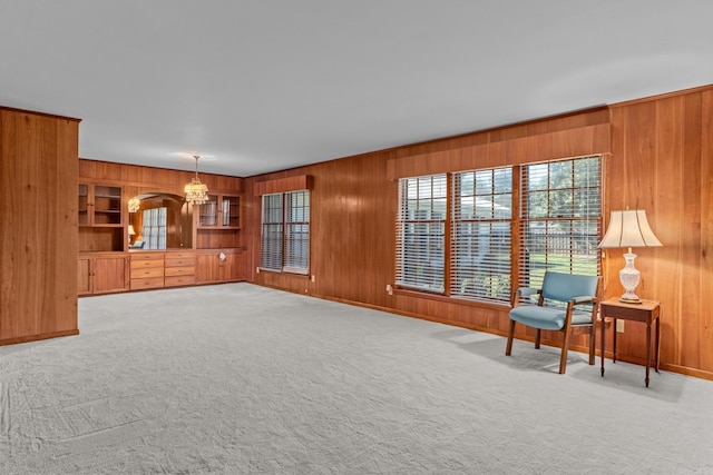 unfurnished room featuring a notable chandelier, wood walls, and carpet flooring