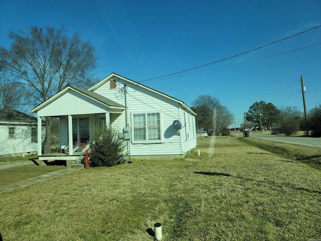 view of side of home with a porch and a yard