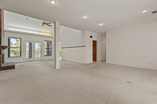 unfurnished room featuring light colored carpet, ceiling fan, and a brick fireplace