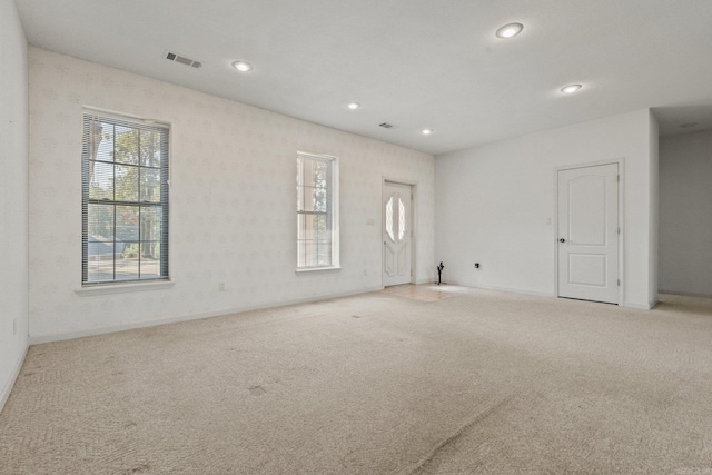 unfurnished room featuring a wealth of natural light and light carpet