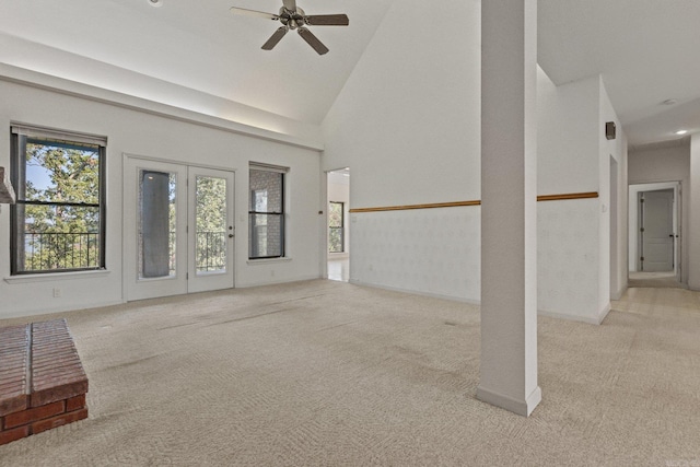 unfurnished living room with baseboards, a ceiling fan, high vaulted ceiling, and light carpet