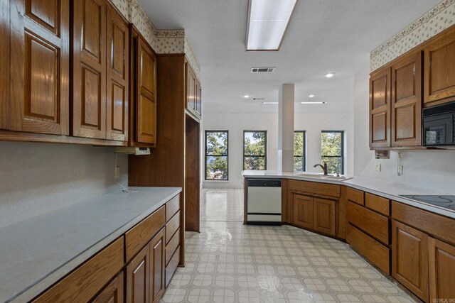 kitchen featuring light countertops, a sink, black appliances, and brown cabinetry