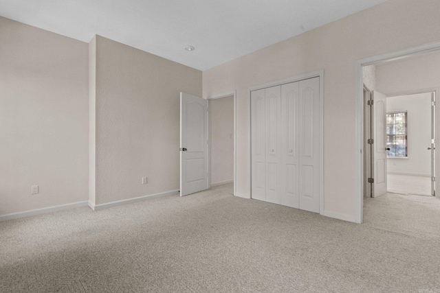 unfurnished bedroom featuring light carpet and a closet