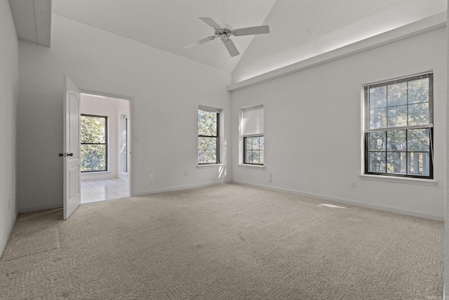 carpeted empty room featuring high vaulted ceiling, ceiling fan, and a healthy amount of sunlight