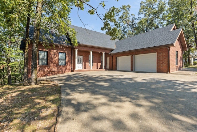 view of front of home featuring brick siding, roof with shingles, a garage, and concrete driveway