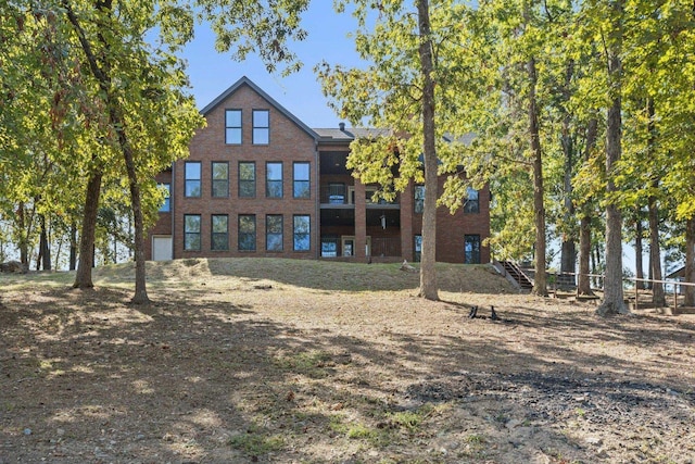 back of property featuring brick siding, stairway, and fence
