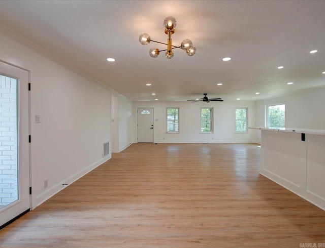 unfurnished living room with ceiling fan with notable chandelier, light hardwood / wood-style floors, and ornamental molding