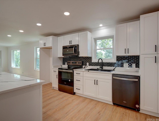 kitchen with white cabinets, stainless steel appliances, light hardwood / wood-style floors, and sink