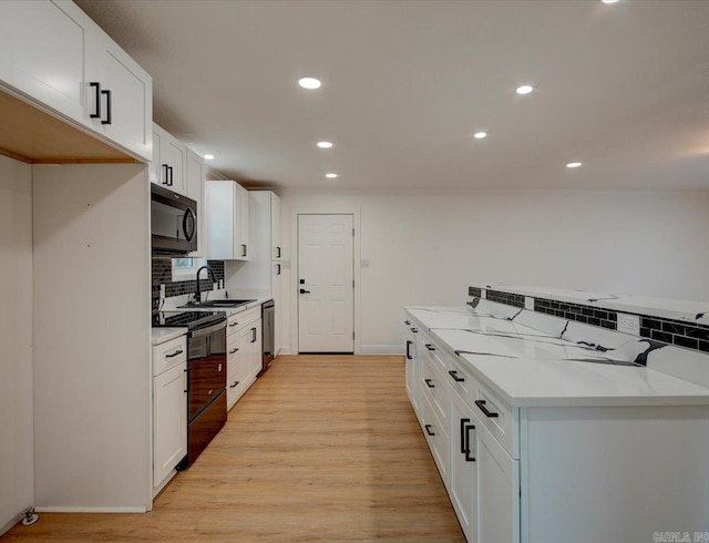 kitchen featuring white cabinets, decorative backsplash, light hardwood / wood-style floors, and black range