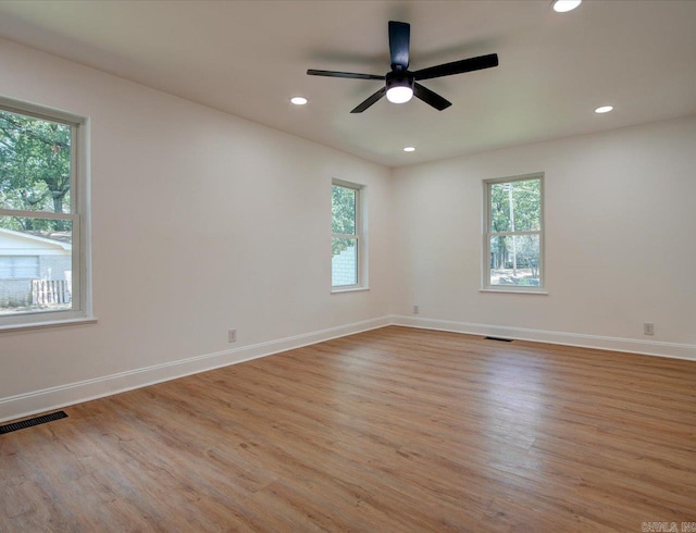 spare room featuring light wood-type flooring, ceiling fan, and a healthy amount of sunlight