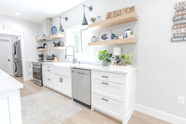 211 Woodland Shores Cir, Clinton, AR 72031 - kitchen with tasteful backsplash, open shelves, stacked washer / drying machine, appliances with stainless steel finishes, and wall chimney exhaust hood