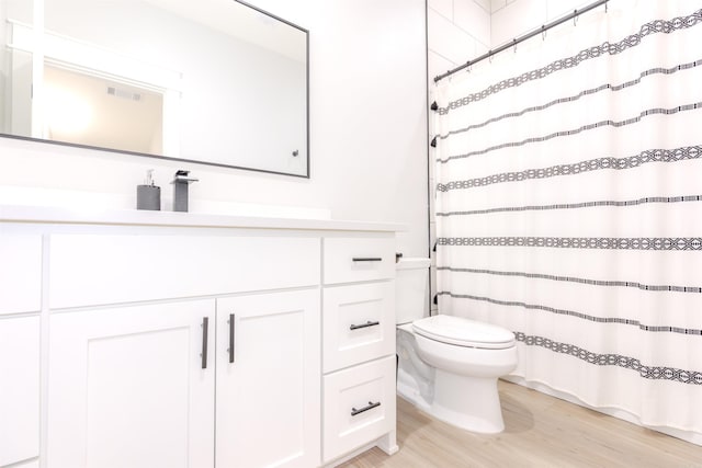 bathroom with walk in shower, vanity, toilet, and hardwood / wood-style flooring