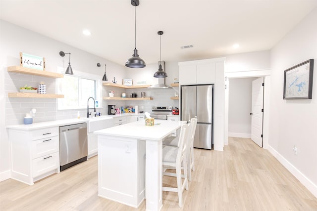 kitchen featuring a center island, stainless steel appliances, white cabinetry, a kitchen breakfast bar, and decorative backsplash