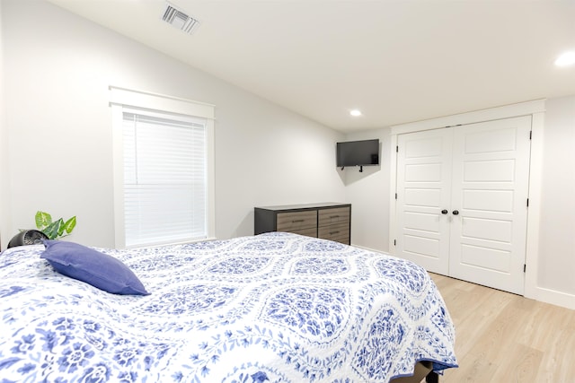 bedroom with a closet, light hardwood / wood-style floors, and vaulted ceiling