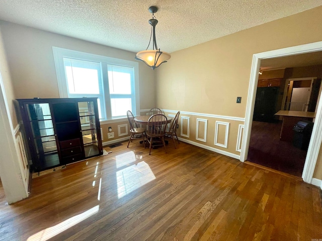 unfurnished dining area featuring a textured ceiling and dark wood-type flooring