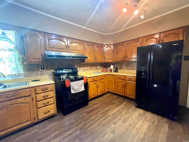 kitchen with black appliances, ornamental molding, hardwood / wood-style flooring, and tasteful backsplash