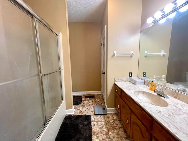 full bathroom with a textured ceiling, vanity, toilet, and combined bath / shower with glass door