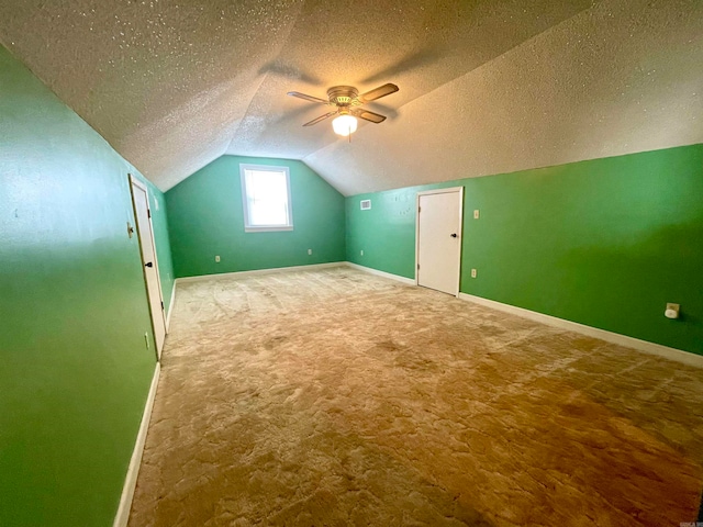 additional living space with lofted ceiling, a textured ceiling, ceiling fan, and carpet