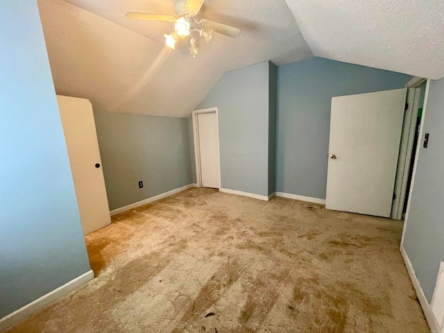 additional living space featuring lofted ceiling, ceiling fan, light carpet, and a textured ceiling