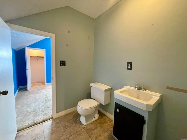 bathroom with vanity, lofted ceiling, toilet, and tile patterned floors