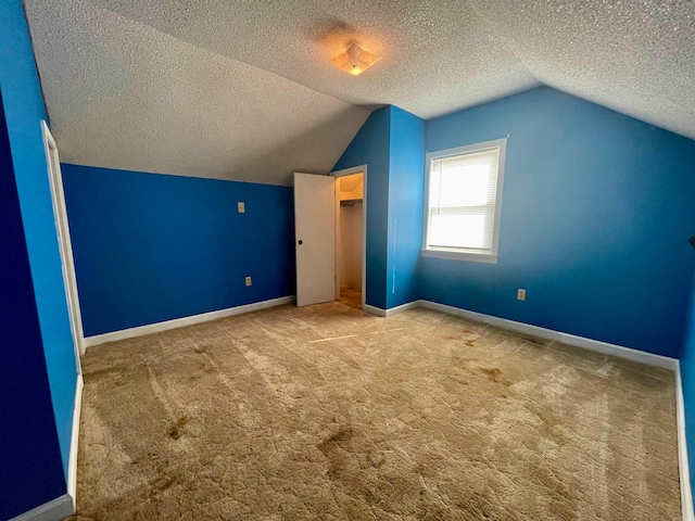 additional living space with lofted ceiling, light colored carpet, and a textured ceiling