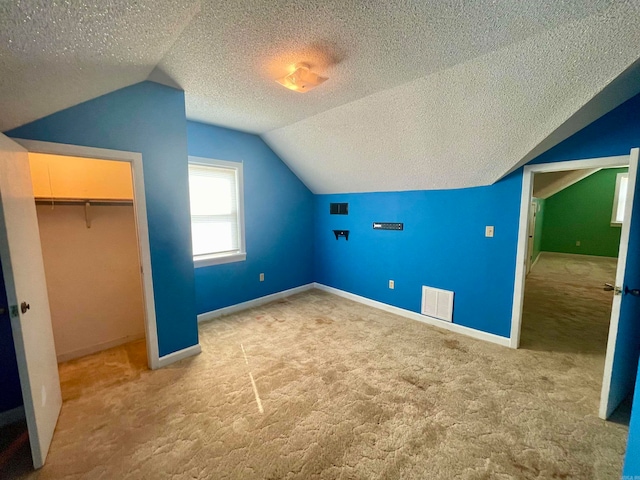 additional living space with vaulted ceiling, a textured ceiling, and carpet flooring